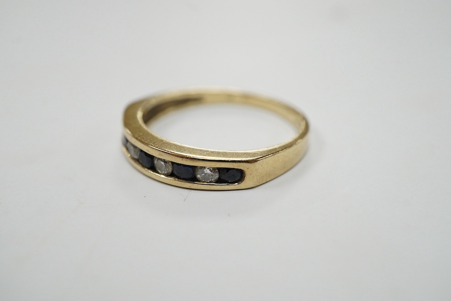 A modern 9ct gold and channel set sapphire and diamond set half hoop ring, size N/O, gross weight 2.2 grams. Condition - fair